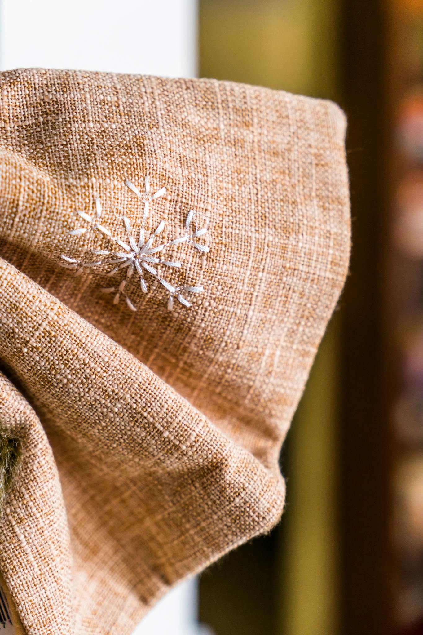 Close-up of a burlap fabric with snowflake embroidery, showcasing winter-themed decor.