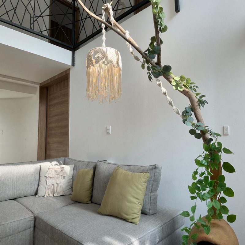 Una lámpara diseñada por Musgo Studio cuelga de una rama decorativa en una sala.